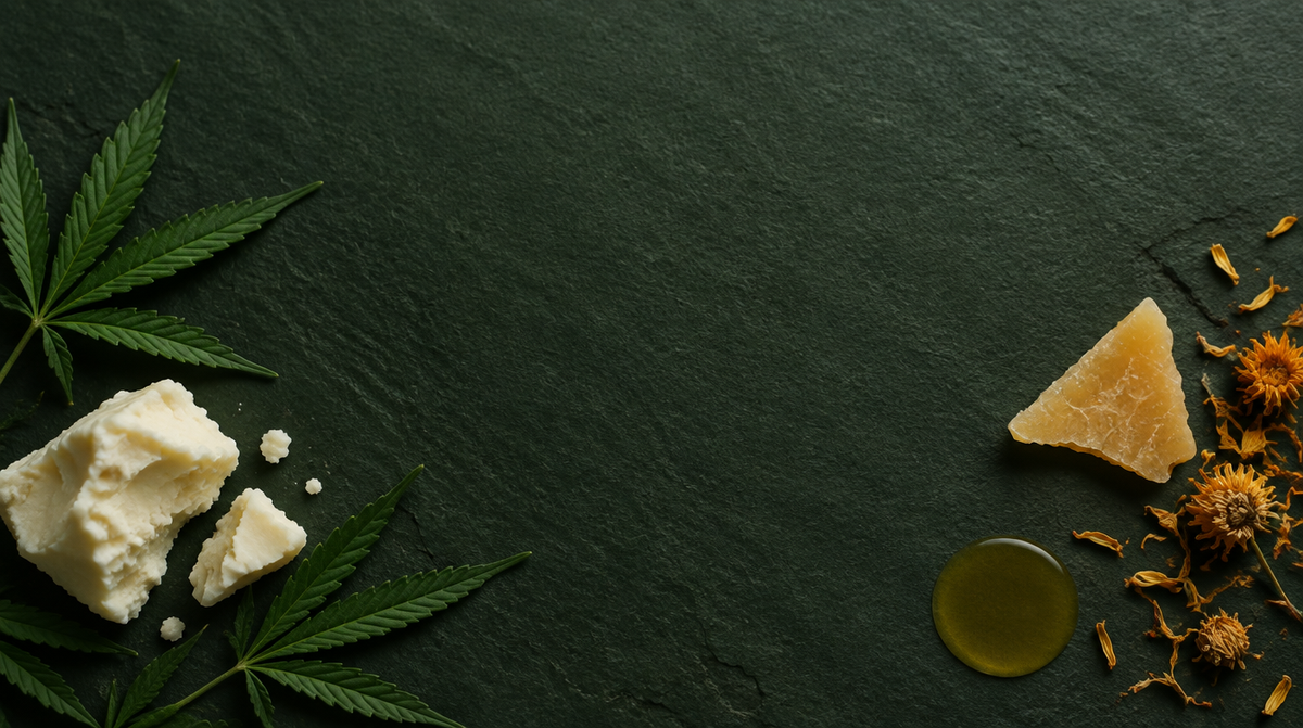 Hemp leaves, raw shea butter, beeswax and dried calendula arranged on dark slate