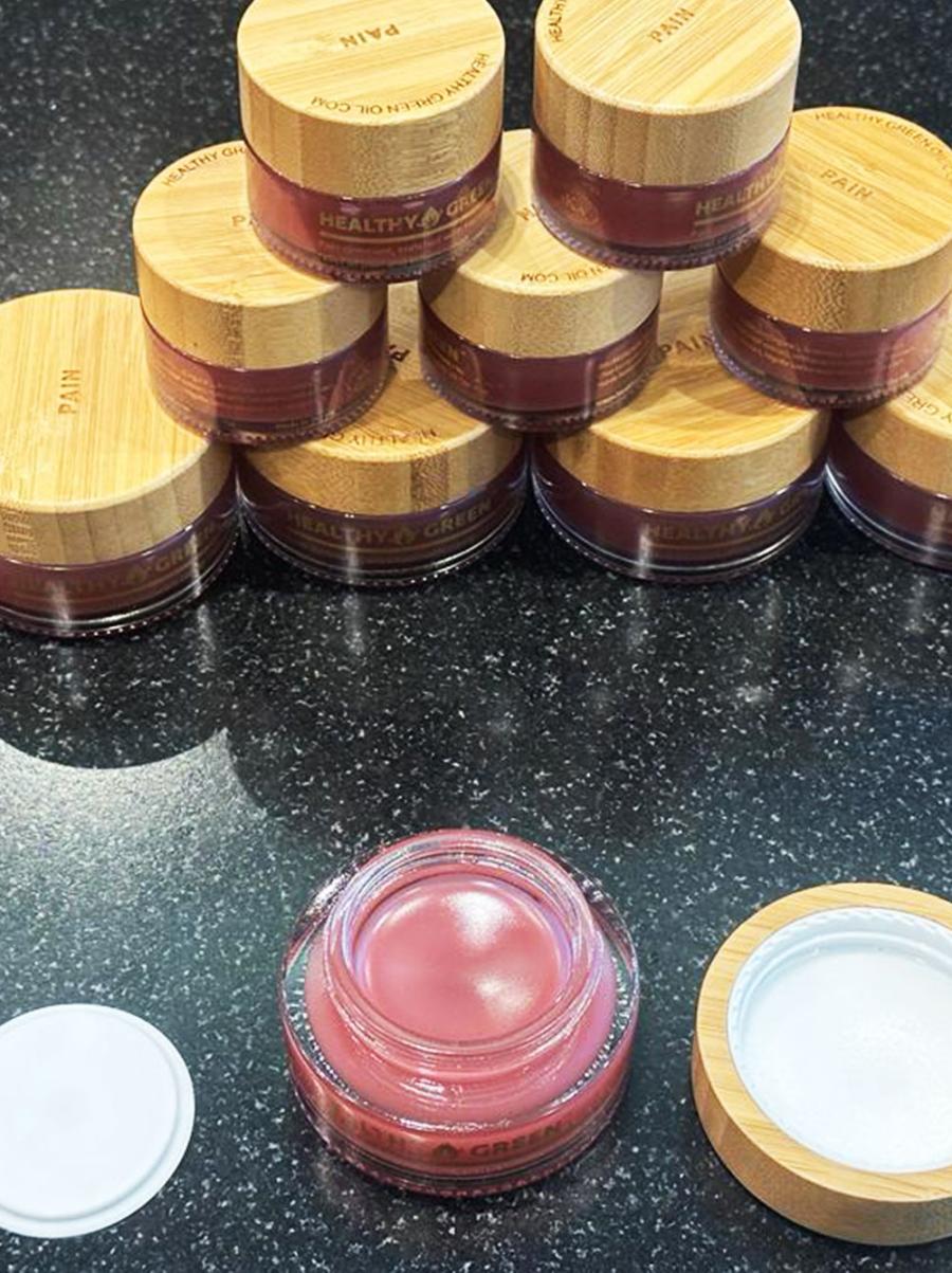 Healthy Green balm jars grouped on a dark slate surface
