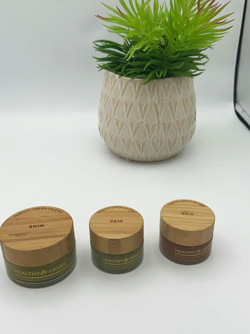 Two Healthy Green balm jars, one open and one closed, on a pale surface