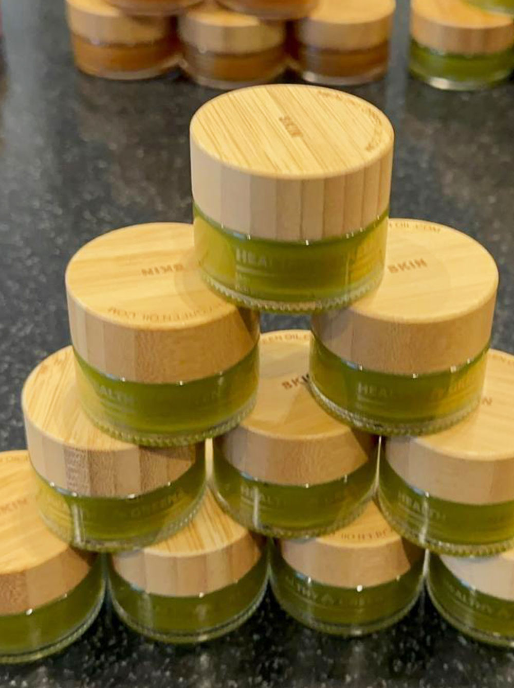 Healthy Green balm jars grouped on a dark slate surface